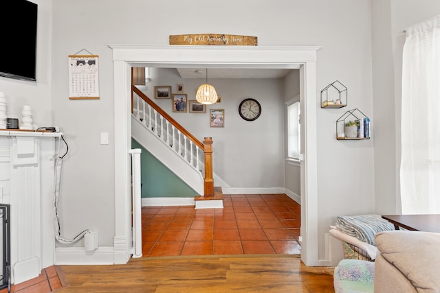 tiled entryway featuring stairs and baseboards