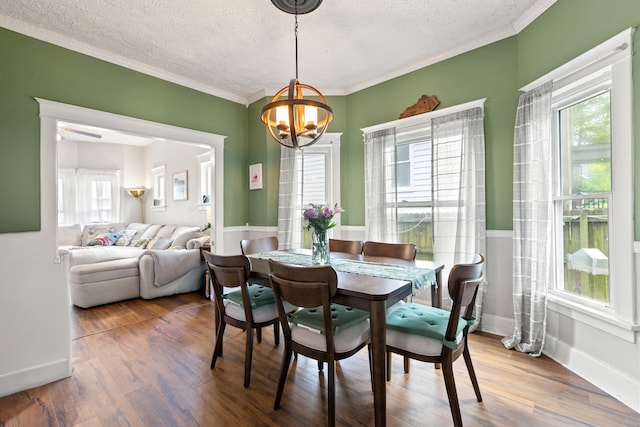 dining space with a textured ceiling, a chandelier, plenty of natural light, wood finished floors, and ornamental molding