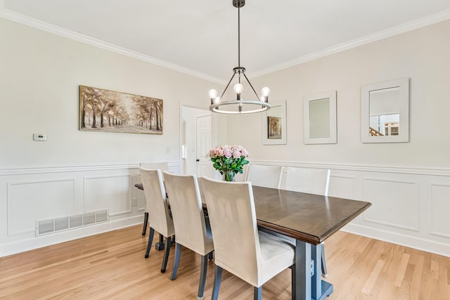 9118 Harrodsburg Rd, Wilmore, KY 40390 - dining area with crown molding, a chandelier, a decorative wall, light wood finished floors, and wainscoting