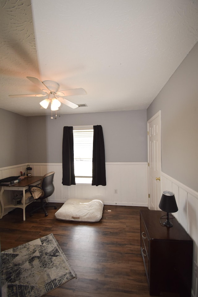 bedroom featuring wainscoting, wood finished floors, and ceiling fan