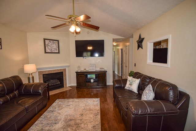living area with vaulted ceiling, dark wood-style floors, ceiling fan, a fireplace, and baseboards