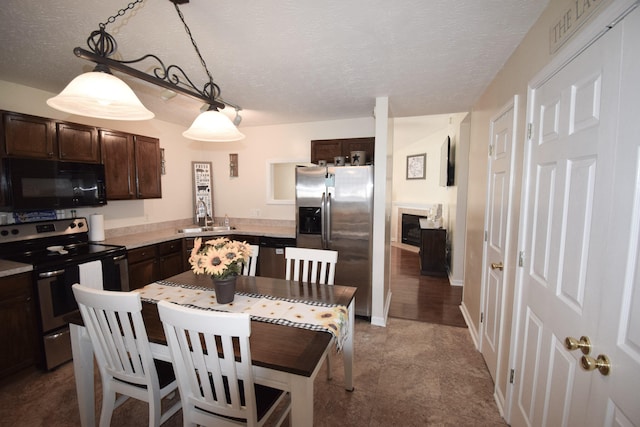 kitchen featuring stainless steel appliances, dark brown cabinetry, a sink, light countertops, and hanging light fixtures