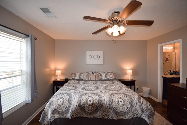 bedroom with baseboards, dark wood-type flooring, a ceiling fan, and ensuite bath