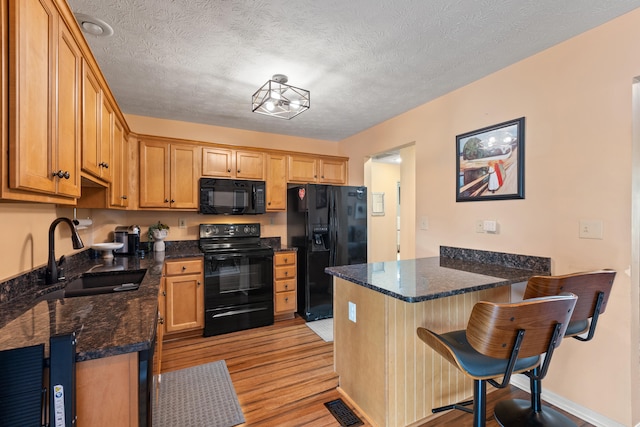 829 Lauderdale Dr, Lexington, KY 40515 - kitchen featuring black appliances, a peninsula, light wood-type flooring, a kitchen breakfast bar, and dark stone countertops