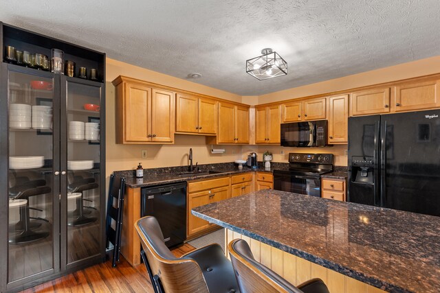 829 Lauderdale Dr, Lexington, KY 40515 - kitchen with black appliances, wood finished floors, dark stone counters, a breakfast bar area, and a textured ceiling