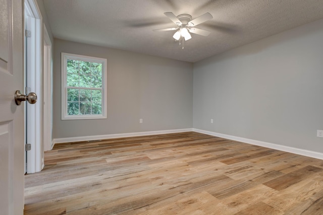 spare room featuring light wood-type flooring, ceiling fan, baseboards, and a textured ceiling