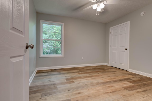 unfurnished room with a ceiling fan, light wood finished floors, baseboards, and a smoke detector