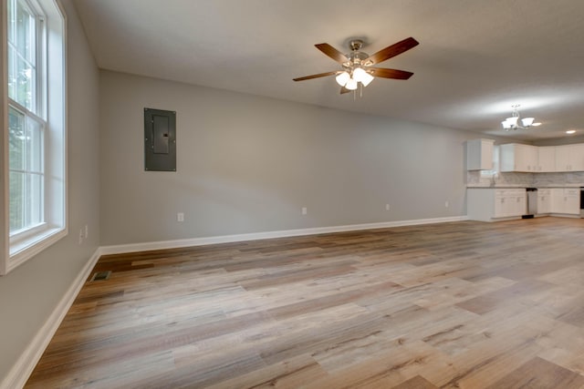 unfurnished living room featuring electric panel, a chandelier, light wood-style flooring, and baseboards