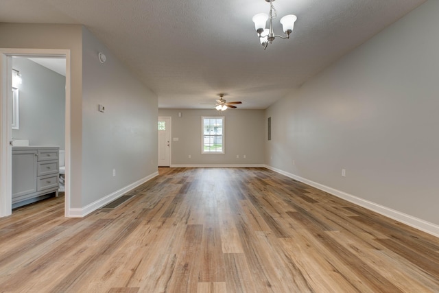 spare room featuring a chandelier, light wood-style flooring, baseboards, and a ceiling fan