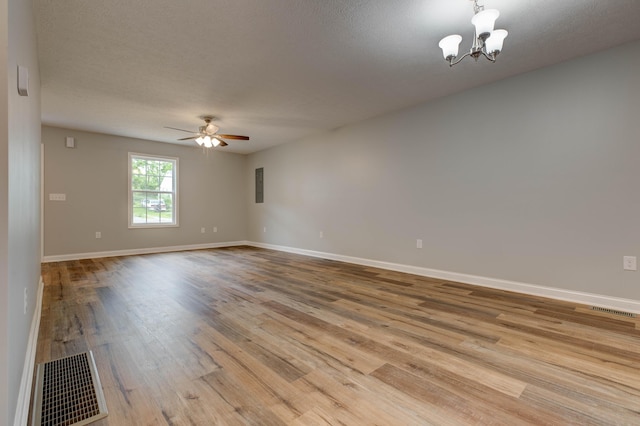 empty room with a chandelier, wood finished floors, baseboards, ceiling fan, and a textured ceiling
