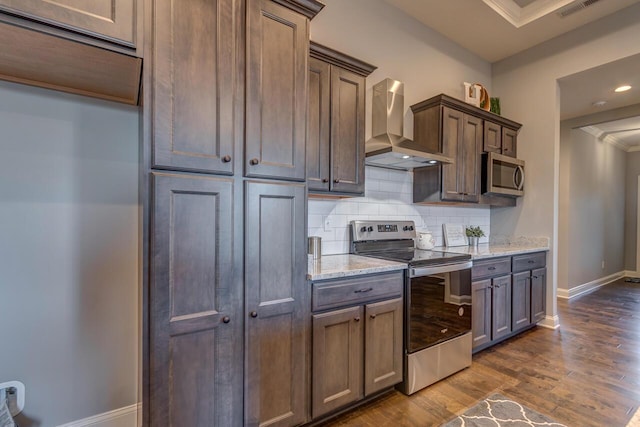 kitchen featuring appliances with stainless steel finishes, wall chimney range hood, backsplash, dark wood-type flooring, and baseboards
