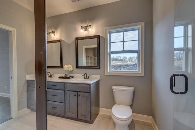 full bath featuring toilet, double vanity, and baseboards