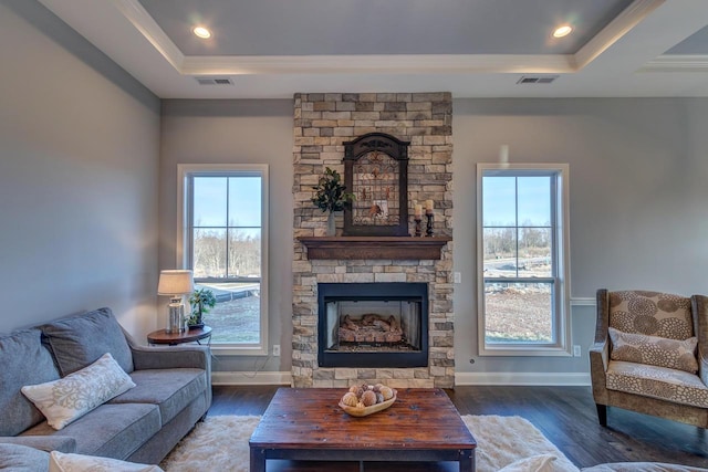 living room with a tray ceiling, plenty of natural light, wood finished floors, and crown molding