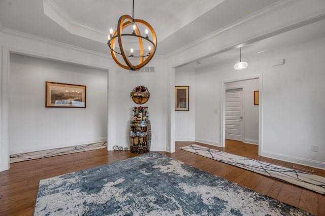 unfurnished room featuring a chandelier, wood-type flooring, ornamental molding, and baseboards