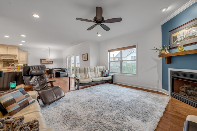 living area with recessed lighting, ceiling fan, crown molding, wood finished floors, and baseboards