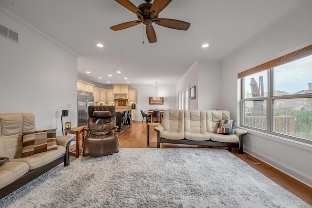 living room featuring ornamental molding, light wood-type flooring, recessed lighting, ceiling fan, and baseboards