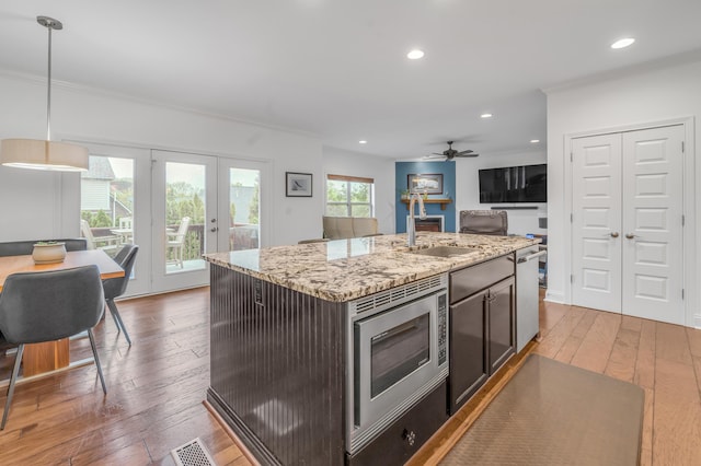 kitchen with appliances with stainless steel finishes, a sink, hardwood / wood-style floors, crown molding, and a ceiling fan