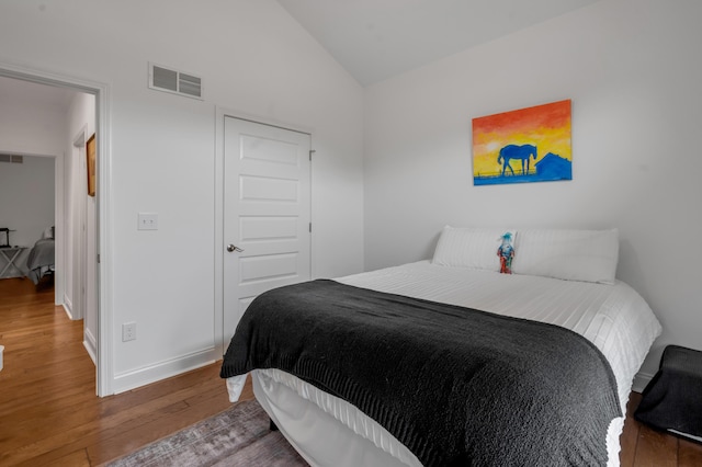 bedroom featuring wood-type flooring, lofted ceiling, and baseboards