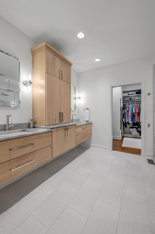 bathroom featuring vanity, recessed lighting, baseboards, and a spacious closet