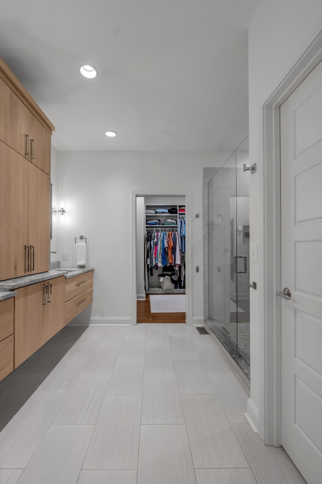 full bathroom featuring vanity, a shower stall, recessed lighting, baseboards, and a spacious closet