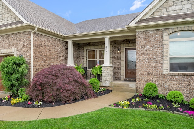 doorway to property with covered porch, roof with shingles, and brick siding