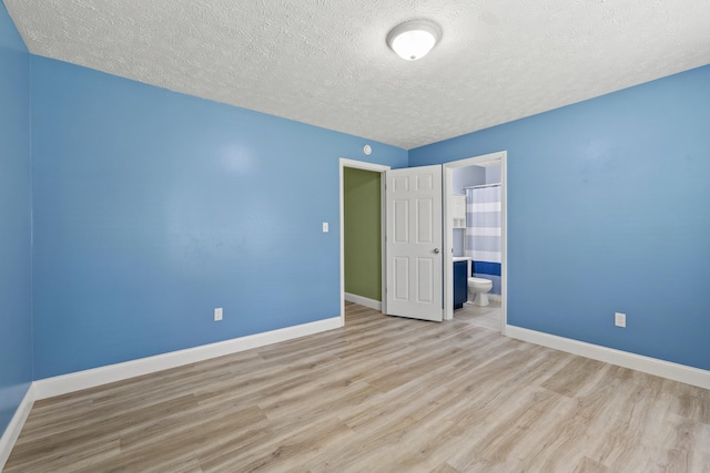 120 Chestnut Ln, Versailles, KY 40383 - unfurnished bedroom featuring wood finished floors, a textured ceiling, baseboards, and connected bathroom