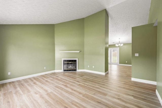 120 Chestnut Ln, Versailles, KY 40383 - unfurnished living room featuring a textured ceiling, a chandelier, light wood-type flooring, a fireplace, and baseboards