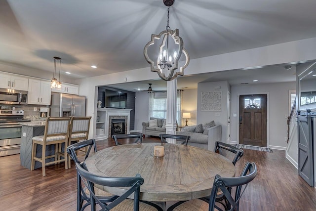 dining area featuring healthy amount of natural light, dark wood-type flooring, a fireplace, and recessed lighting