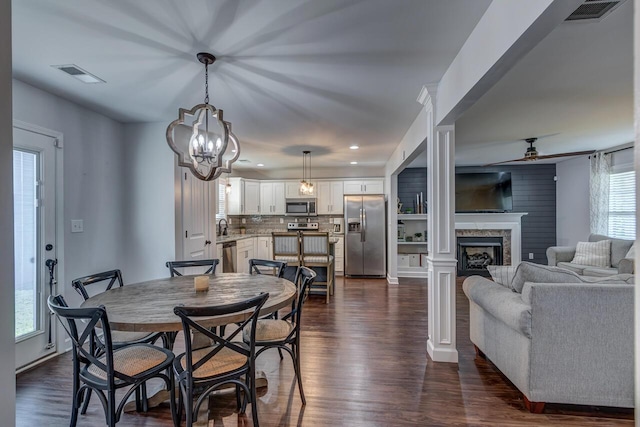 dining space with dark wood finished floors, a fireplace, ceiling fan, recessed lighting, and a chandelier