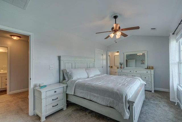 bedroom with vaulted ceiling, light carpet, baseboards, ensuite bathroom, and a ceiling fan