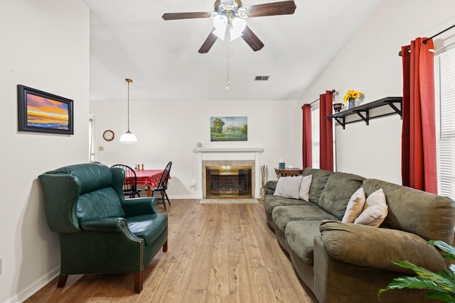 living room featuring lofted ceiling, ceiling fan, light wood-style floors, a fireplace, and baseboards