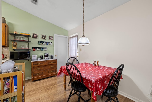 dining area with light wood finished floors, vaulted ceiling, and baseboards