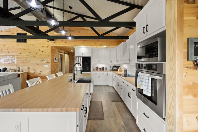 61 Cumberland Cv, Nancy, KY 42544 - kitchen featuring stainless steel appliances, wood walls, dark wood-type flooring, an island with sink, and white cabinetry