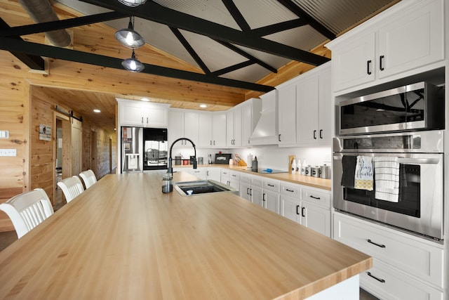 61 Cumberland Cv, Nancy, KY 42544 - kitchen with stainless steel appliances, a sink, premium range hood, white cabinetry, and wooden walls