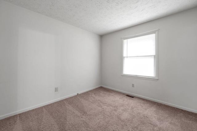 unfurnished room featuring a textured ceiling, carpet, and baseboards