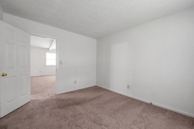 carpeted spare room featuring baseboards and a textured ceiling