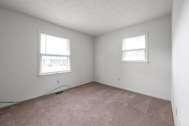 spare room featuring carpet flooring, a textured ceiling, and baseboards