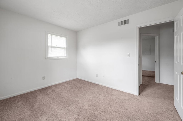 carpeted spare room with a textured ceiling and baseboards