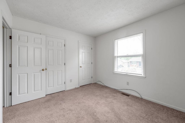 unfurnished bedroom with carpet floors, a textured ceiling, and baseboards