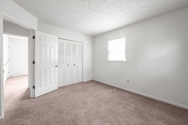 unfurnished bedroom with carpet, a closet, baseboards, and a textured ceiling