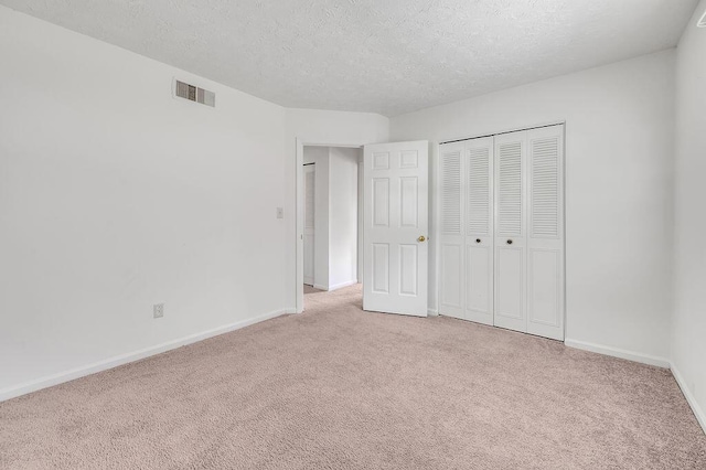 unfurnished bedroom featuring carpet flooring, a textured ceiling, baseboards, and a closet
