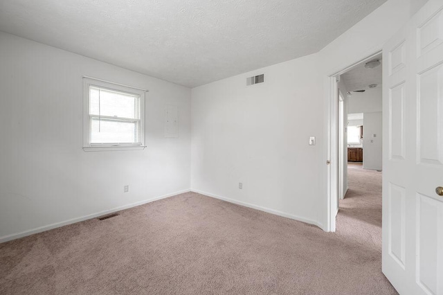 empty room with carpet, a textured ceiling, and baseboards