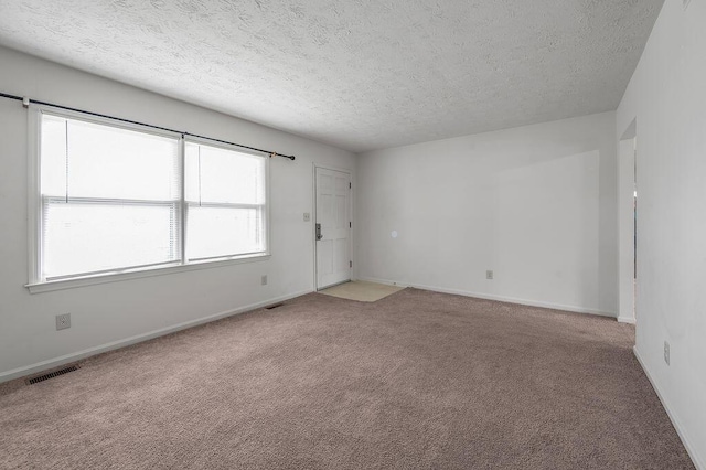 unfurnished room with carpet floors, a textured ceiling, and baseboards