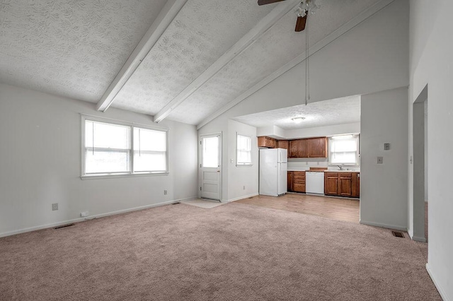 unfurnished living room with light colored carpet, a textured ceiling, plenty of natural light, a ceiling fan, and baseboards