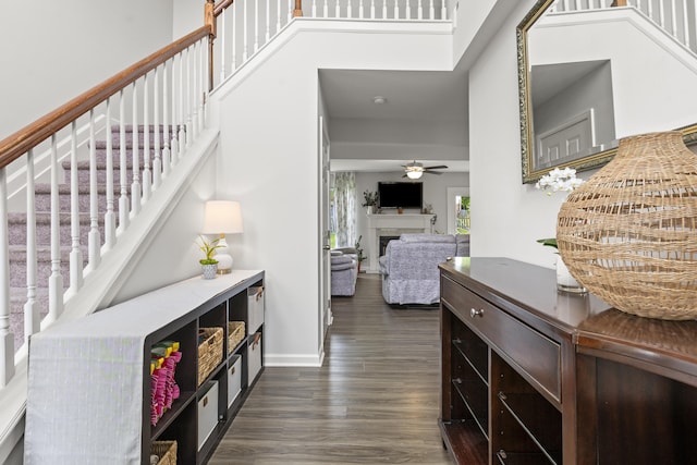 entryway featuring stairway, dark wood-type flooring, a fireplace, and a ceiling fan
