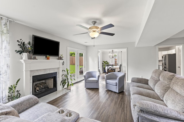 living room featuring ceiling fan, a high end fireplace, dark wood-type flooring, and a chandelier