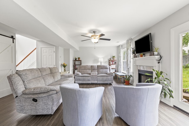 living room featuring a high end fireplace, a barn door, and wood finished floors