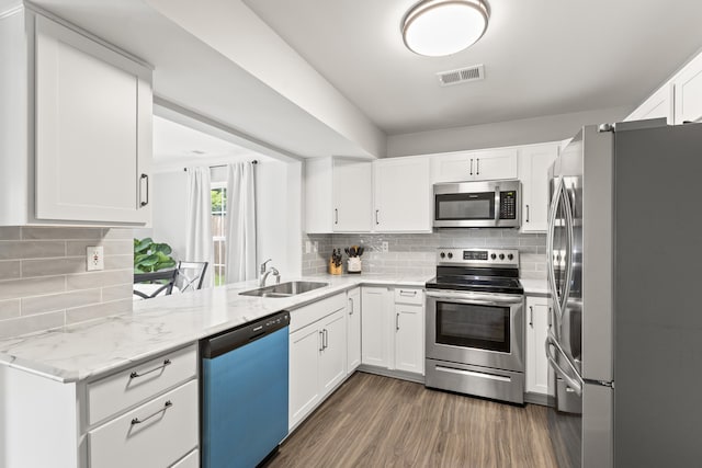 kitchen with stainless steel appliances, a sink, backsplash, and white cabinetry