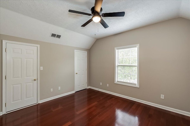 unfurnished bedroom featuring lofted ceiling, wood finished floors, baseboards, a textured ceiling, and a ceiling fan