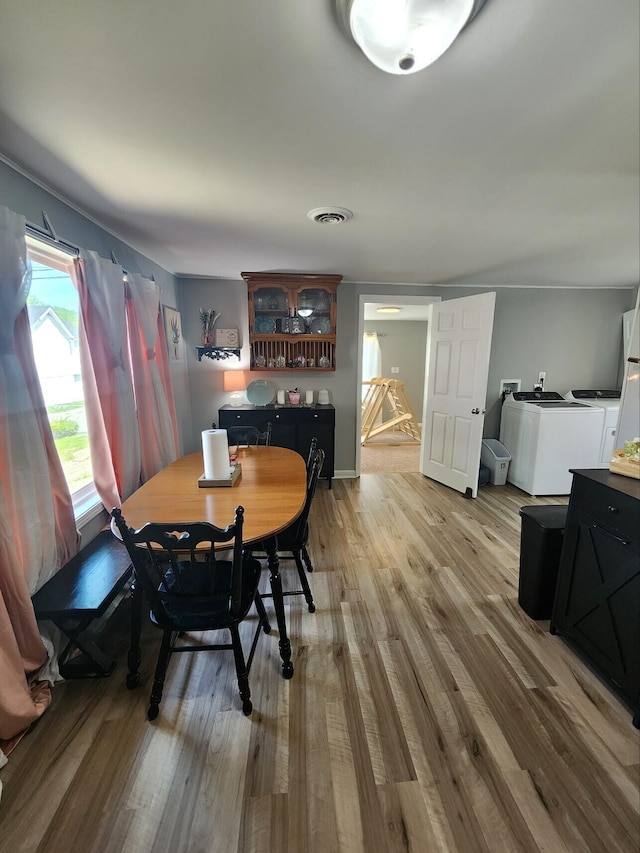 dining area with separate washer and dryer and light wood-type flooring